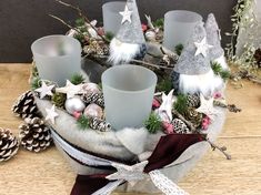 a basket filled with candles and pine cones on top of a wooden table next to christmas decorations