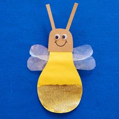 a paper bee on a blue surface with gold glitters around its wings and eyes