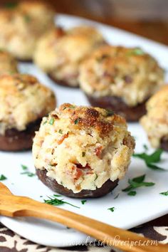 stuffed mushrooms on a white plate with a wooden spoon