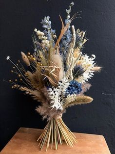 an arrangement of dried flowers on a wooden table