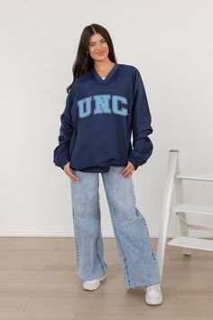 Stay comfortable and show your school spirit with our North Carolina Tar Heels Classic V-Neck Wind Shirt featuring a bold college logo. Designed for style and functionality, this lightweight layer offers wind protection with a timeless v-neck design, perfect for game days or casual outings. Collegiate Navy Top For Game Day, Navy Varsity Top For College, Collegiate Blue Tops For Campus, Blue Collegiate Tops For Campus, Blue Sporty Tops For Campus, Sporty Blue Tops For Campus, Navy Collegiate Top For College, Navy Collegiate Style Top, Blue Varsity Tops For Campus