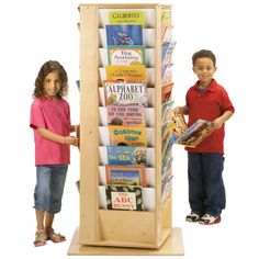 two children are standing next to a book stand