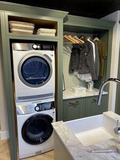 a washer and dryer in a small room with green cabinets, marble counter tops