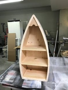 a wooden boat sitting on top of a table next to a shelf filled with books