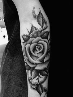 a black and white photo of a rose with leaves on it's arm, done by