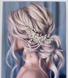 a woman with blonde hair and a flower in her hair is wearing a wedding hairstyle