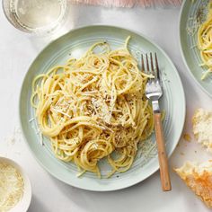 a plate of spaghetti with parmesan cheese on top and bread slices next to it