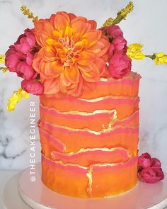 an orange and pink cake with flowers on top