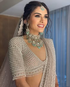 a woman in a bridal gown with jewelry on her neck and shoulders, smiling at the camera