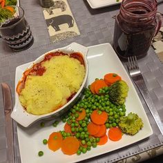 a white plate topped with food next to broccoli and carrots on a table