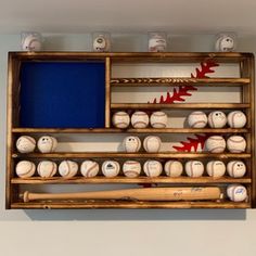 baseballs and bats are arranged in a wooden box on the wall, with blue screen behind them