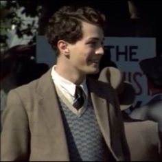 a man wearing a suit and tie standing in front of a sign that says the news