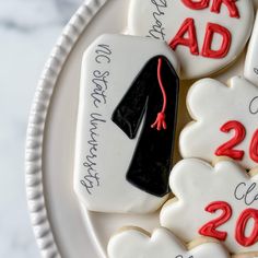 decorated cookies with graduation caps and gowns are on a white plate that says congratulations