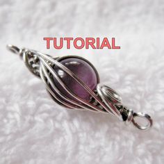 a wire wrapped pendant with a purple bead hanging from it's end on a white background