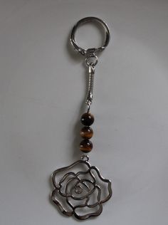 a key chain with a rose and beads hanging from it's side on a white surface