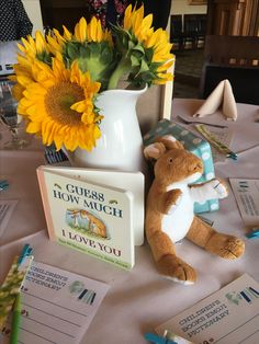 there is a stuffed animal next to a book and sunflowers on the table