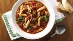 a white bowl filled with pasta and broccoli on top of a wooden table