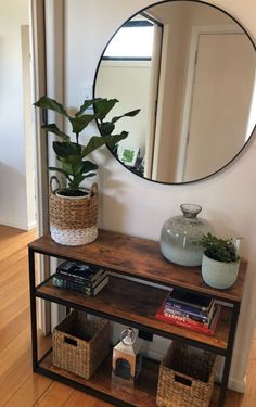 a mirror sitting on top of a wooden shelf next to a potted plant and books