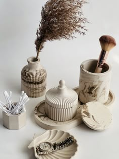 an assortment of ceramic objects on a white surface with a feather sticking out of one of the vases