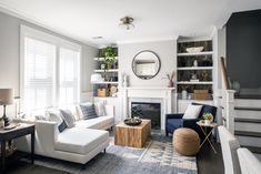 a living room filled with furniture and a fire place in front of a mirror on the wall