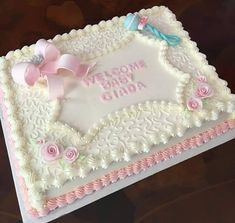 a baby shower cake is decorated with pink flowers and ribbon on the bottom, and welcome baby ciada written in white frosting