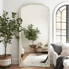 a living room with a large mirror on the wall next to a couch and potted plant