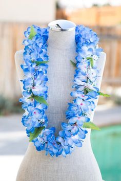 a white mannequin with blue flowers and green leaves on it's neck