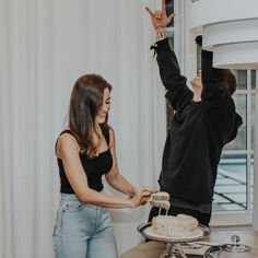 a man and woman reaching for a cake on a table