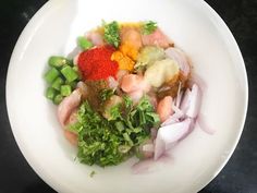 a white bowl filled with vegetables and seasoning on top of a black countertop