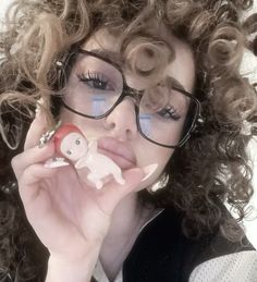 a woman with curly hair and glasses holding a toy