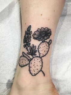 a tattoo on the foot of a woman with flowers and leaves around her ankles, in black ink