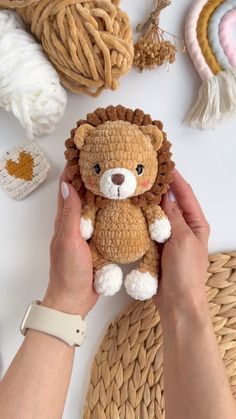 a person holding a stuffed animal in front of some crocheted hats and yarn