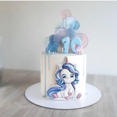 a birthday cake decorated with an image of a unicorn and balloons on the top tier