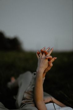 a woman laying on top of a bed holding her hands up