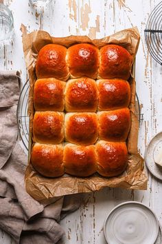 a pan filled with hot cross buns on top of a wooden table next to plates and utensils