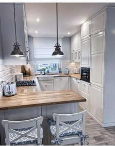 an image of a kitchen setting with white cabinets and wood counter tops in the center