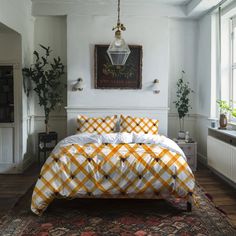 a bed with yellow and white checkered comforter in a room next to a window