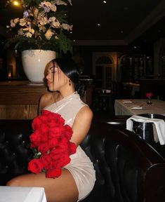 a woman sitting in a chair with red roses