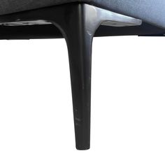 the back end of a black chair with grey fabric and metal legs, against a white background