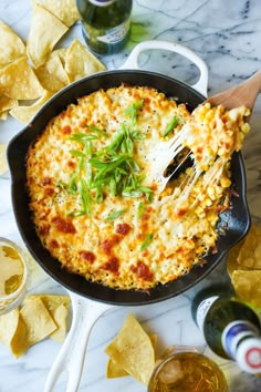 a skillet filled with cheese and tortilla chips on top of a table