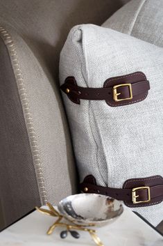 two pieces of luggage sitting on top of a white table next to a pillow and bowl