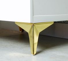 a close up of a white dresser with gold legs on the bottom and side drawers