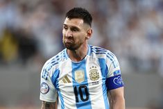 a soccer player with tattoos on his arm and chest looks to the side while standing in front of an audience