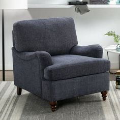 a gray chair sitting on top of a rug in a living room next to a window