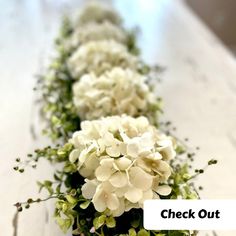 white flowers are lined up along the edge of a counter top with words check out