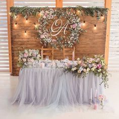 the table is set up with flowers and candles for an elegant wedding reception in front of a wooden wall