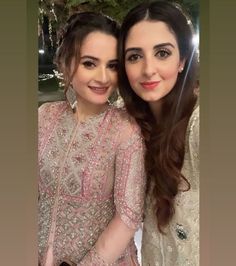 two beautiful women posing for the camera in their wedding outfits, one is wearing a pink outfit