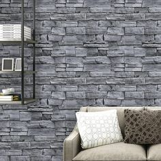 a couch sitting in front of a brick wall next to a shelf filled with books