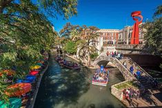 a river filled with lots of boats next to a tall red sculpture on top of a bridge