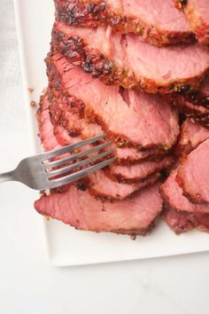 a white plate topped with sliced meat and a fork